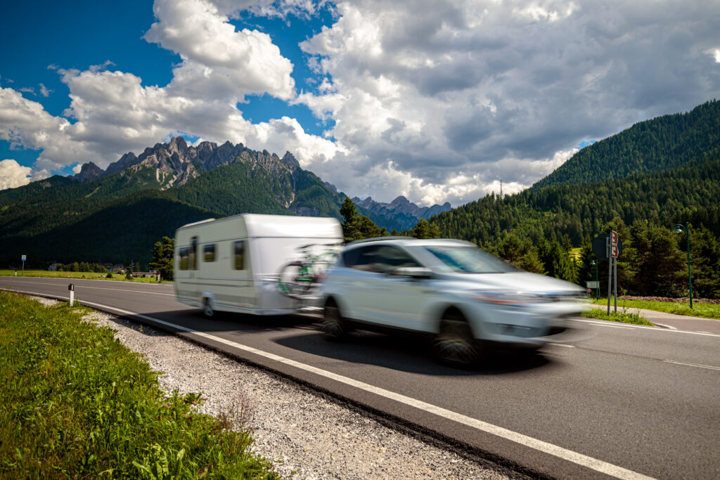 Coche remolcando una caravana por una carretera de montaña