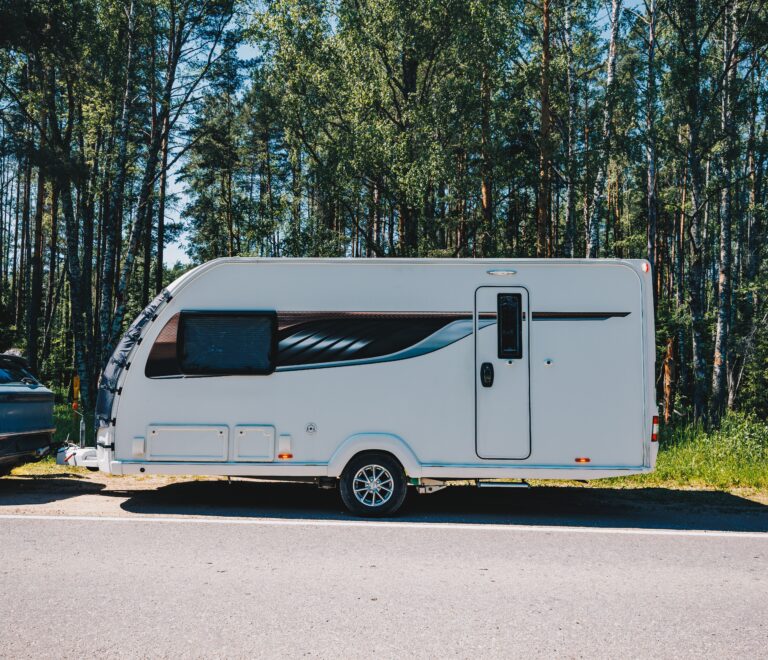 Caravana aparcada junto a un bosque, enganchada a un coche